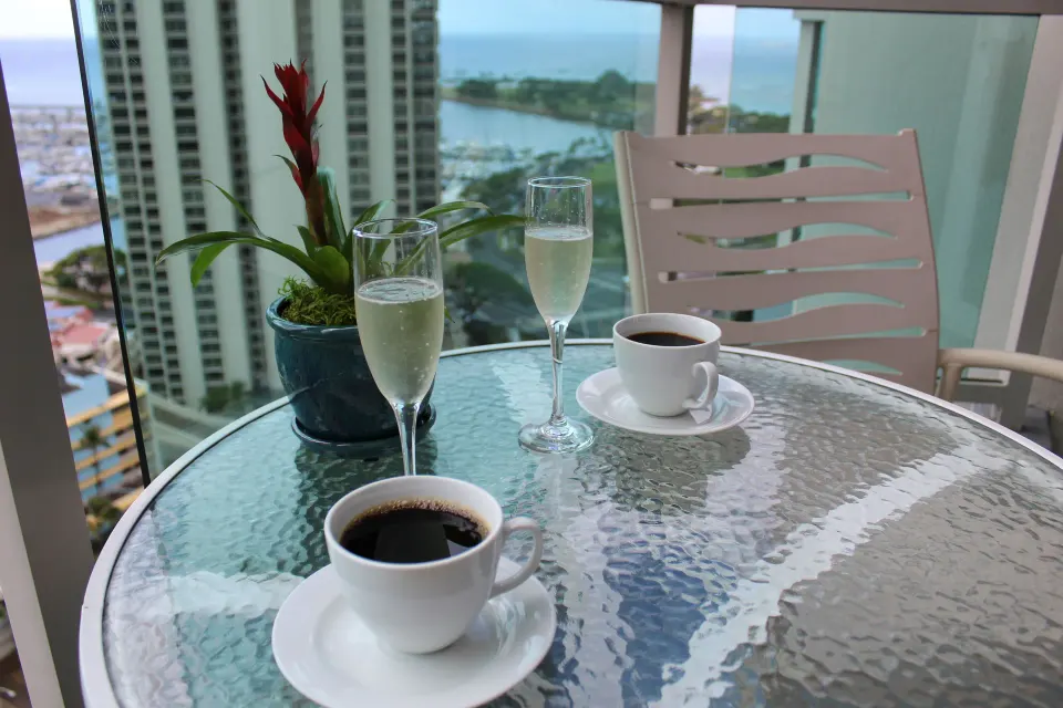 Coffee, sparkling drinks, and a potted plant on a balcony table at Ala Moana Hotel.