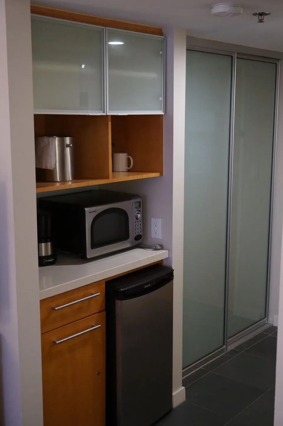 In-room kitchenette cabinet with microwave, mini fridge, coffee maker, and closet at Ala Moana Hotel.