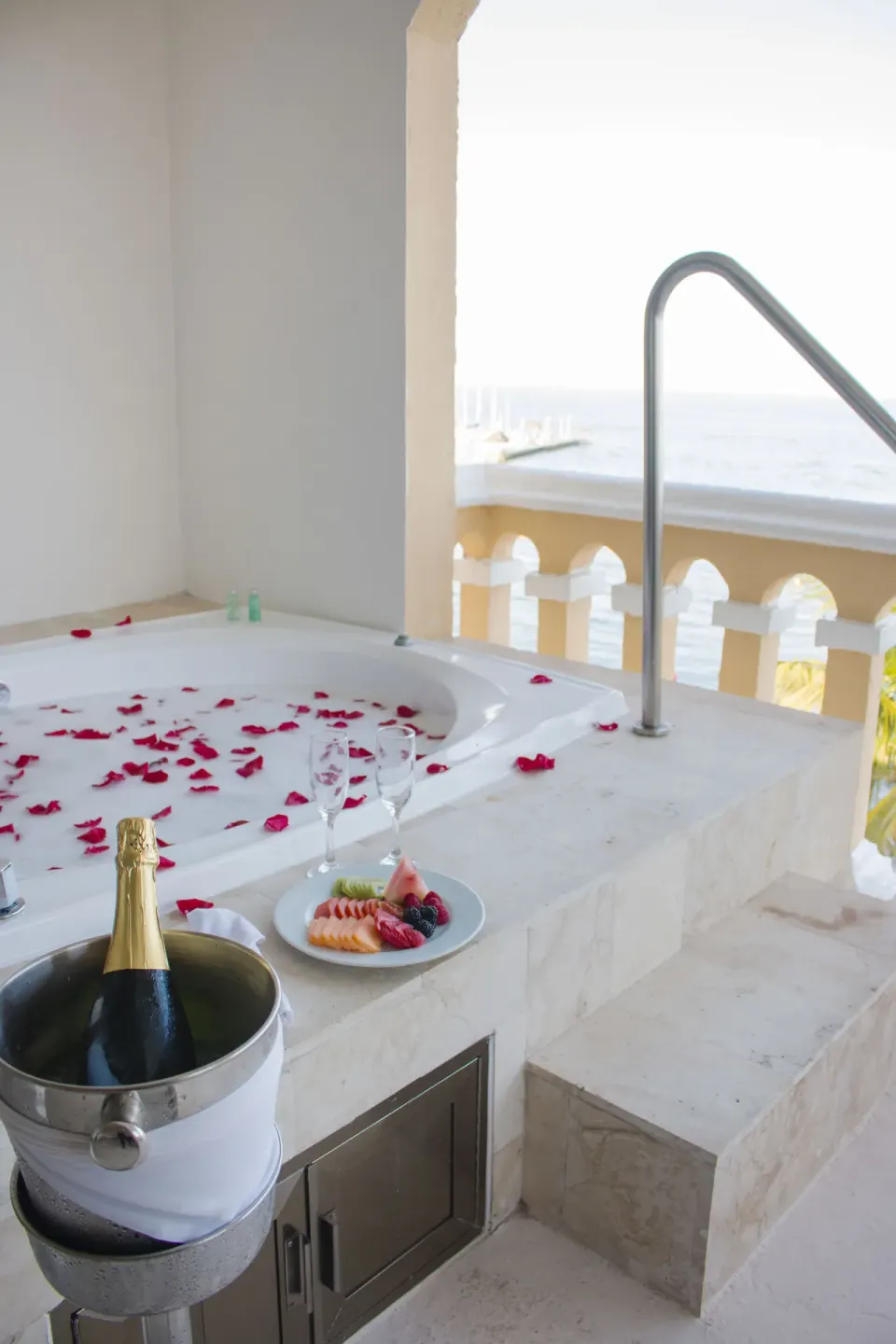 Balcony whirlpool tub with rose petals and ocean view at All Ritmo Cancun Resort & Water Park.