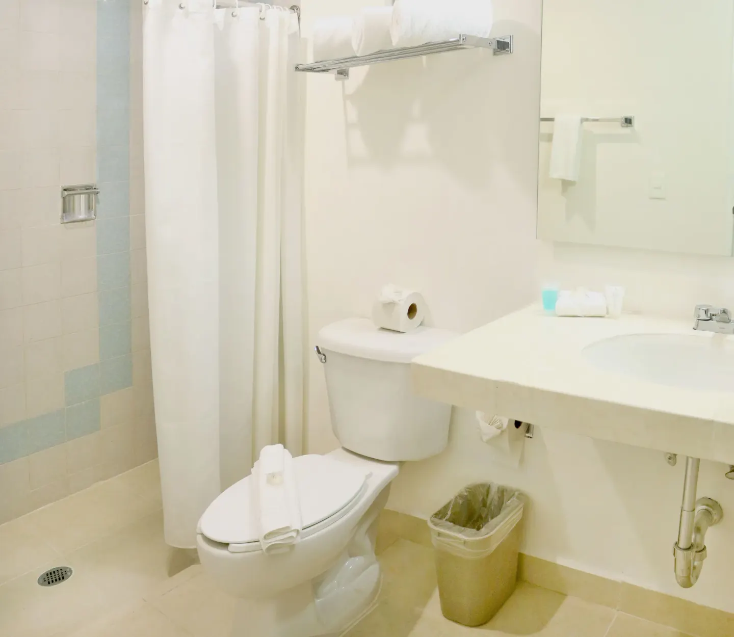 Guest bathroom with shower curtain, toilet, sink, and towel shelf at All Ritmo Cancun Resort & Water Park.