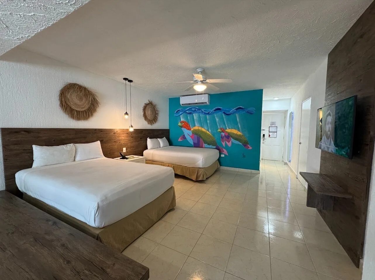 Two-bed guest room with turtle mural and wood accents at All Ritmo Cancun Resort & Water Park.