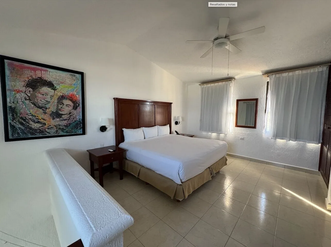 King bed in an upper-level guest room with artwork at All Ritmo Cancun Resort & Water Park.