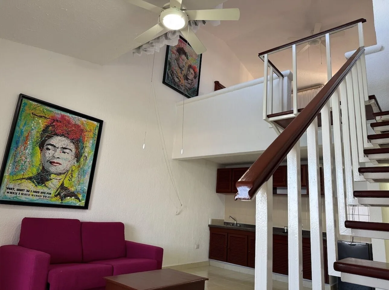Loft living area with staircase and magenta sofa at All Ritmo Cancun Resort & Water Park.