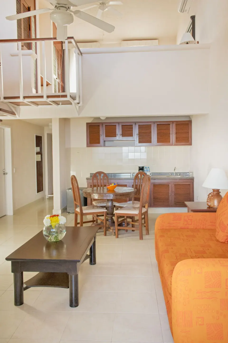 Loft-style suite living area with kitchenette and orange sofa at All Ritmo Cancun Resort & Water Park.
