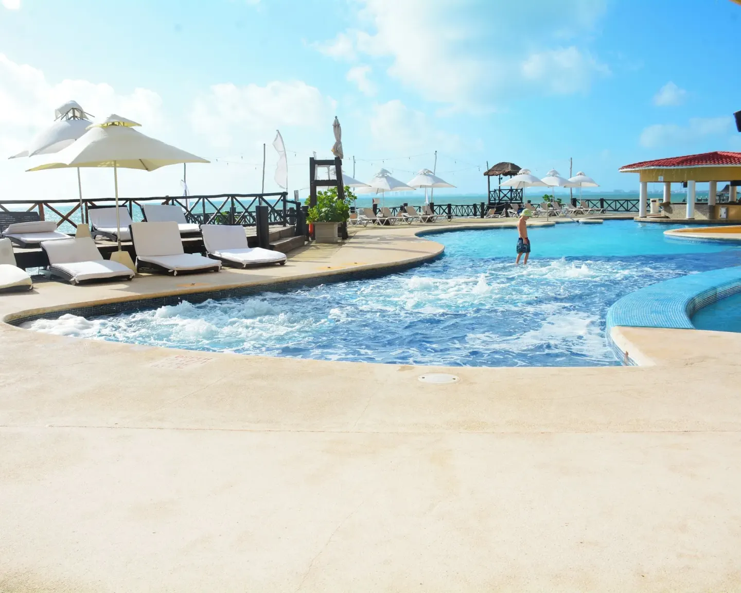 Oceanfront pool with loungers and umbrellas at All Ritmo Cancun Resort & Water Park.