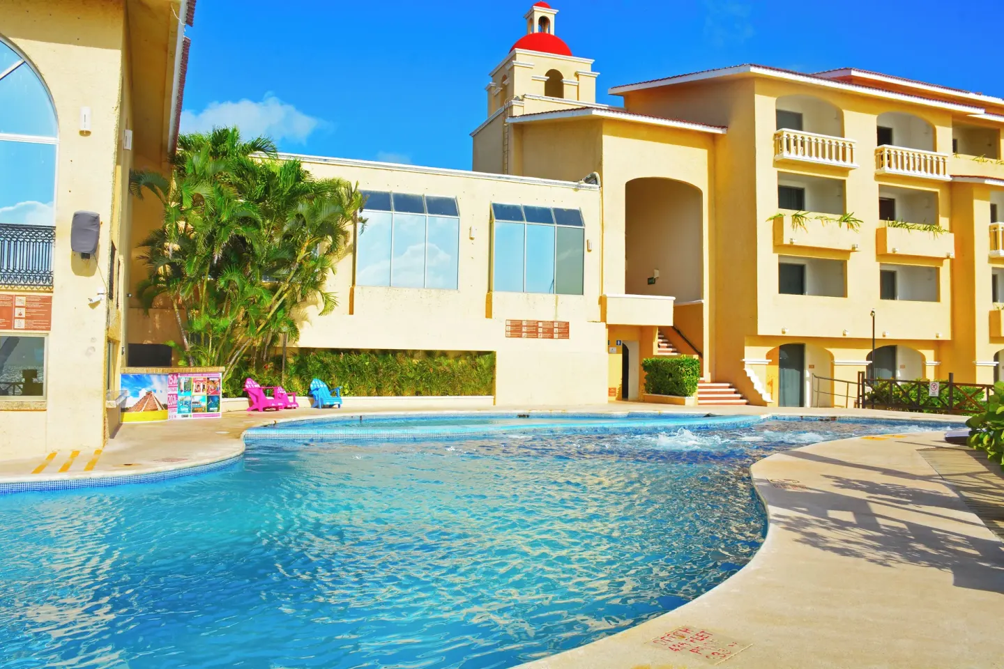 Curving pool beside yellow resort buildings at All Ritmo Cancun Resort & Water Park.