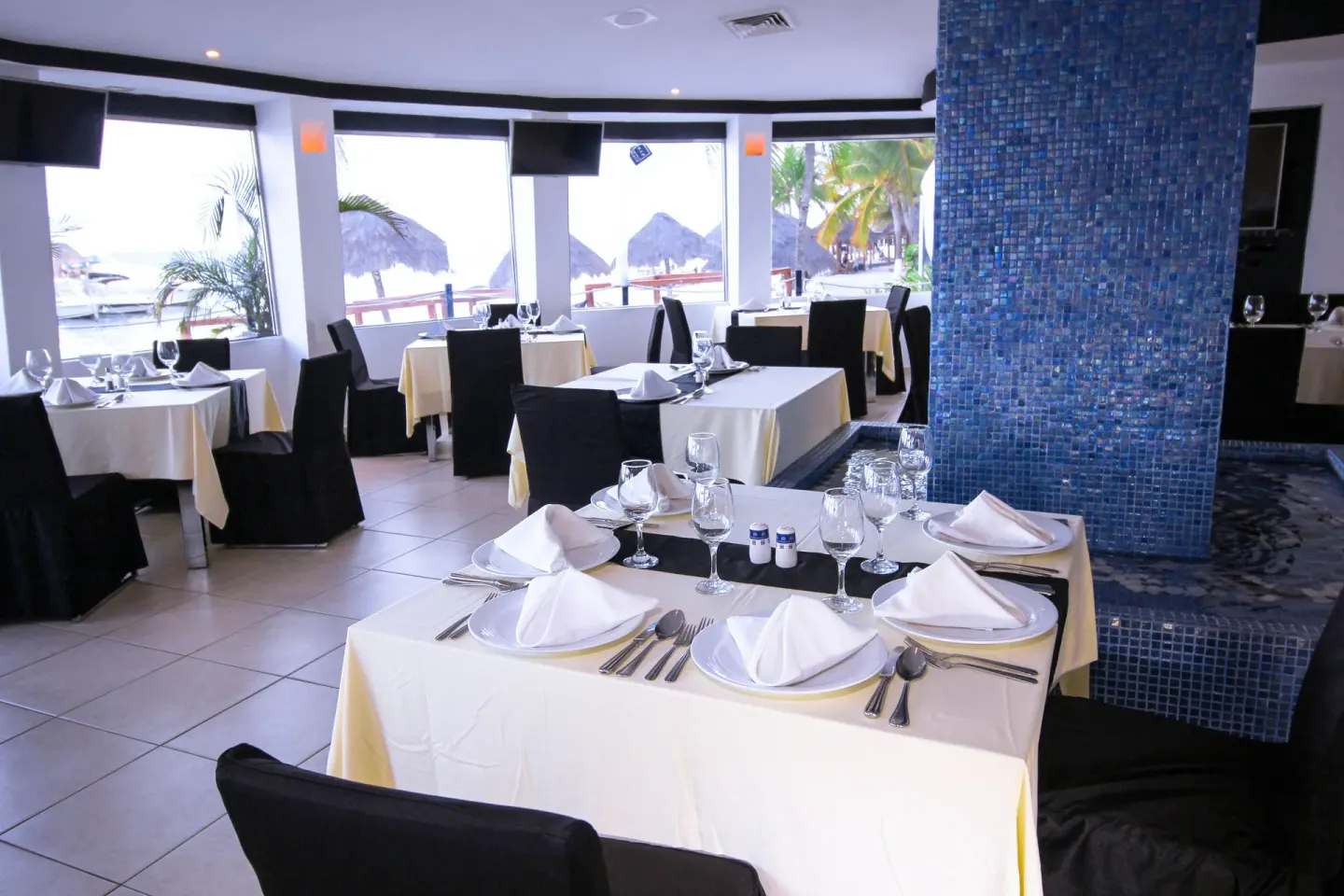 Restaurant tables set by windows at All Ritmo Cancun Resort & Water Park.