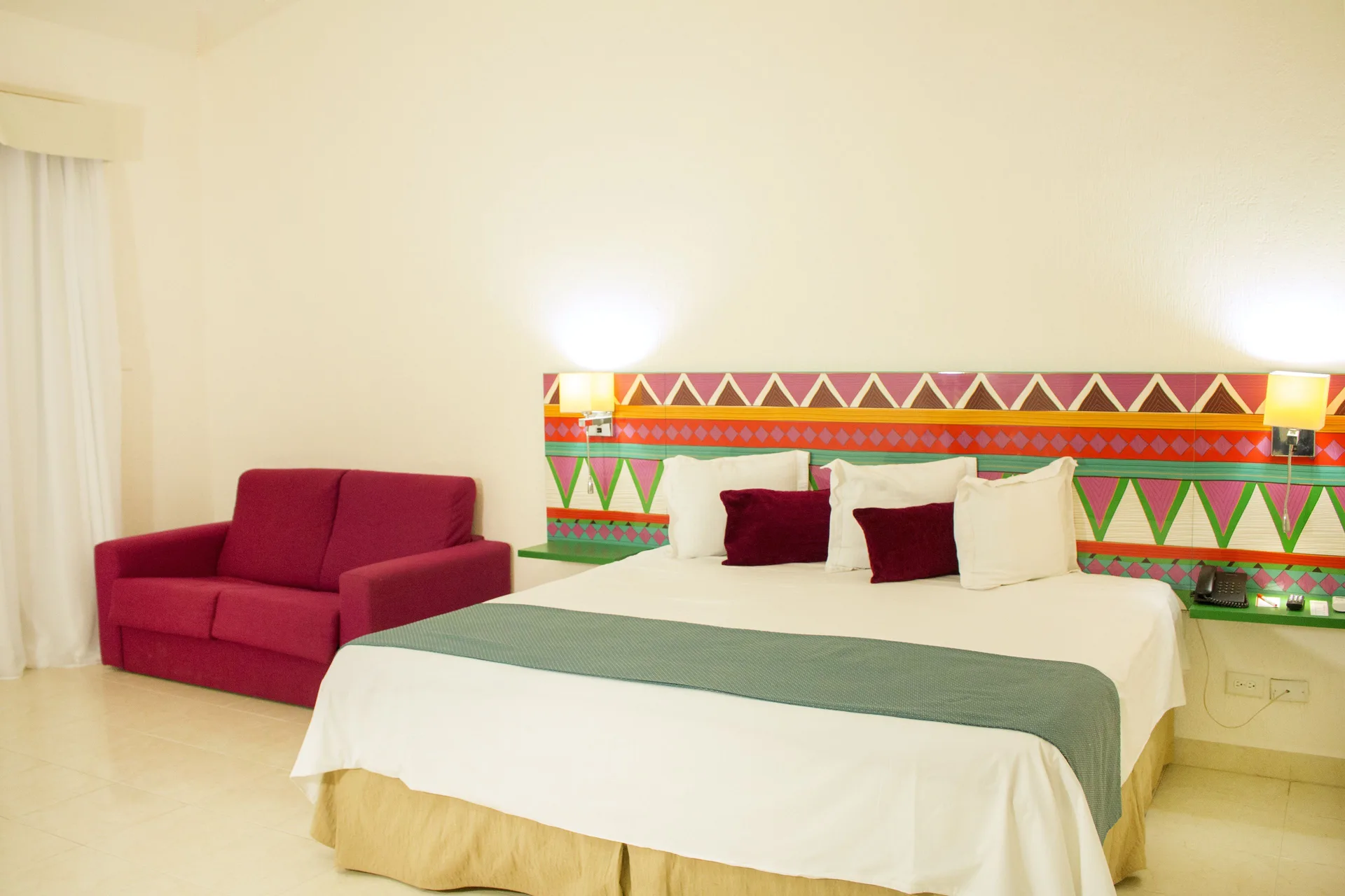 Junior Suite Sea View king bed and red sofa at All Ritmo Cancun Resort & Water Park.