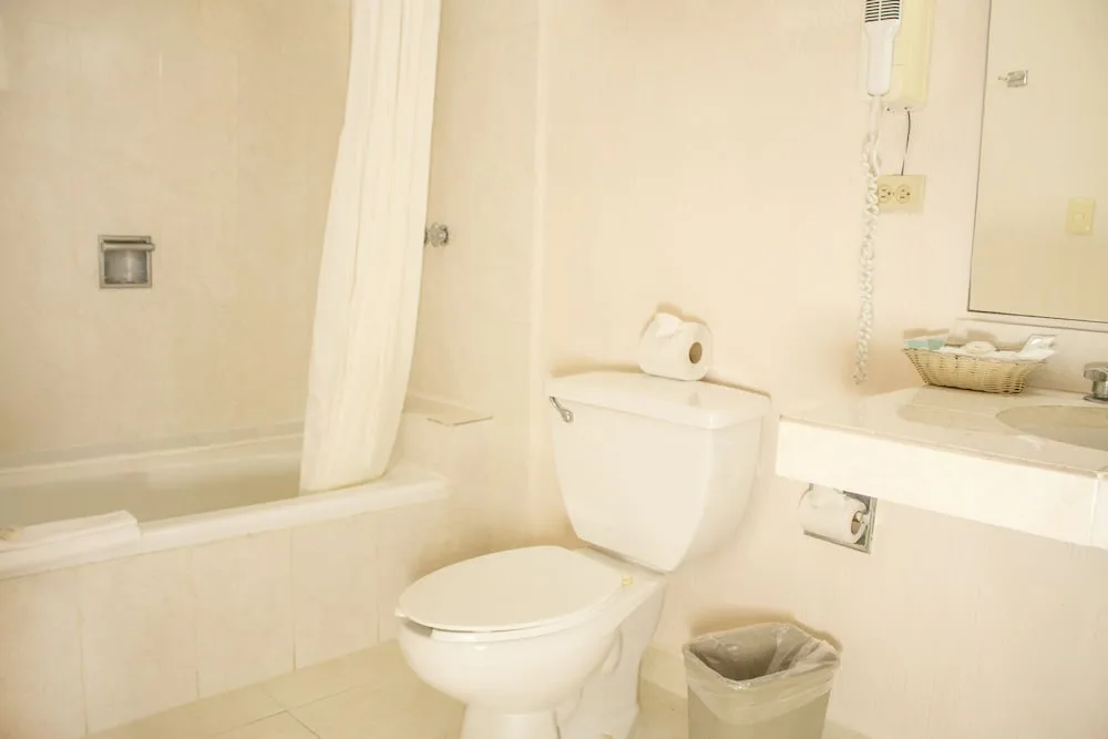 Standard Room bathroom with tub, toilet, and vanity at All Ritmo Cancun Resort & Water Park.