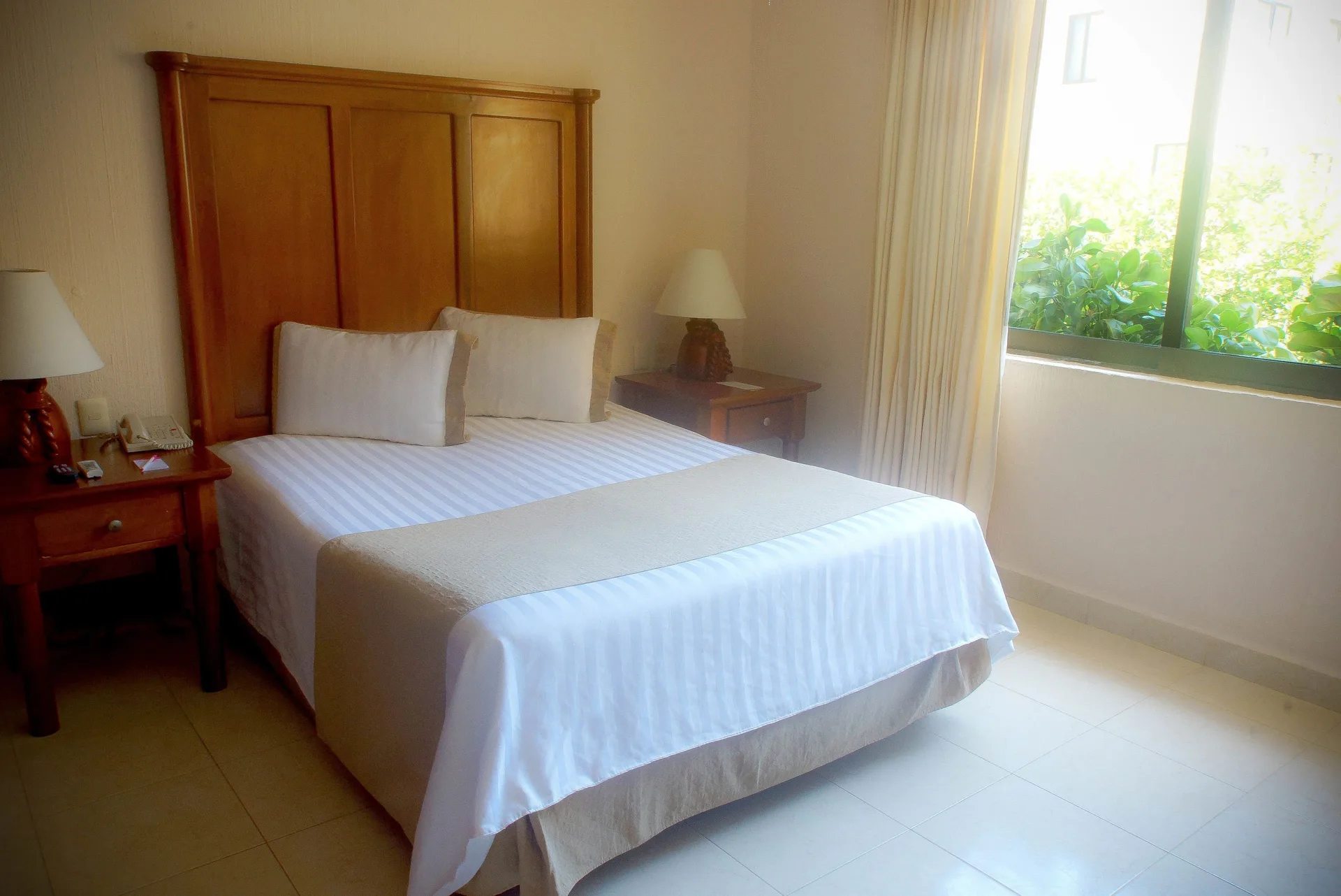 Standard room with one bed beside a bright window at All Ritmo Cancun Resort & Water Park.