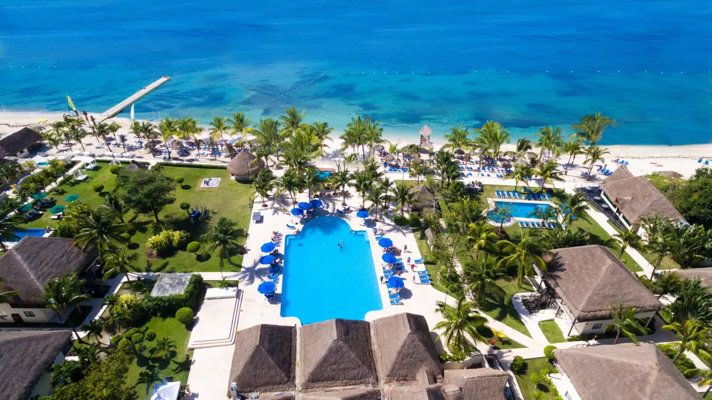 Aerial view of the main pool, beach, pier, palms, and blue sea at Allegro Cozumel.