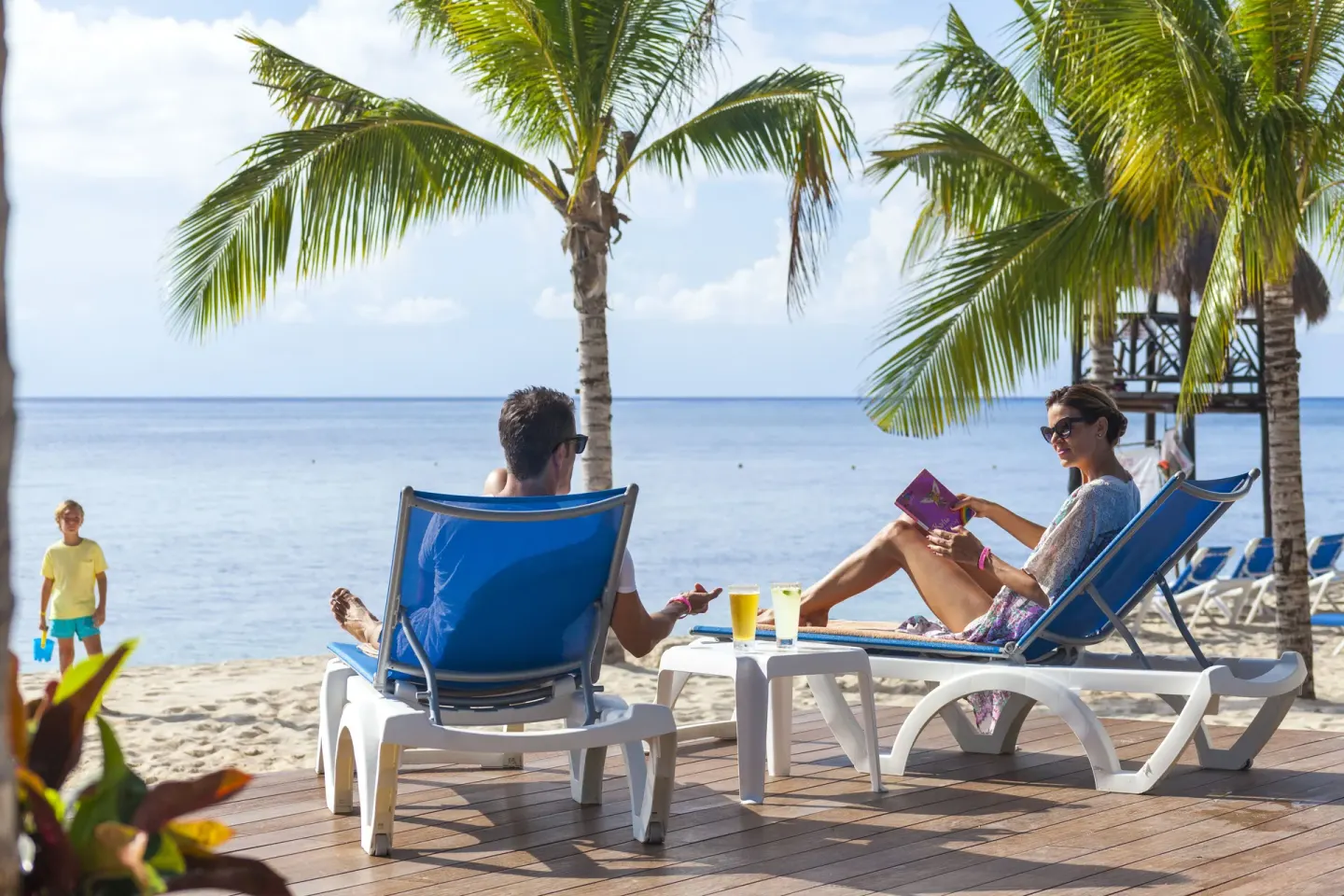 Guests reclining on blue beach loungers by the sea at Allegro Cozumel.