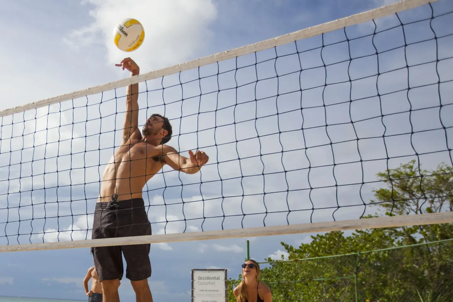 A guest reaches for a volleyball at an outdoor court at Allegro Cozumel.