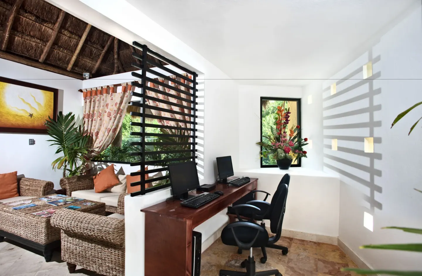 Business corner with computers beside wicker lounge seating at Allegro Cozumel.