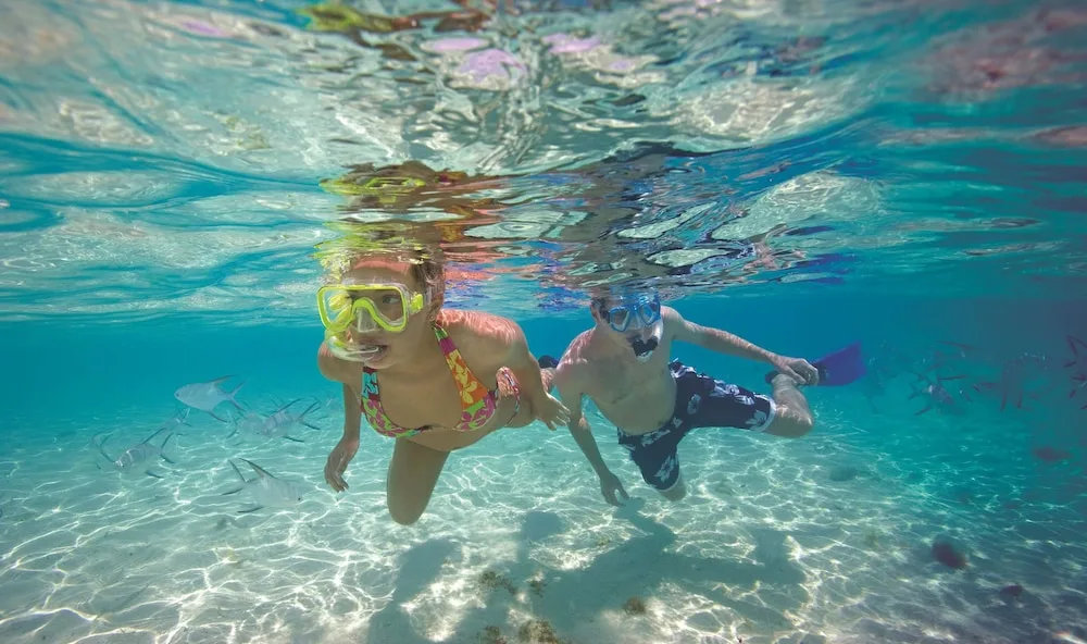 Two children snorkeling underwater in clear sea at Allegro Cozumel.