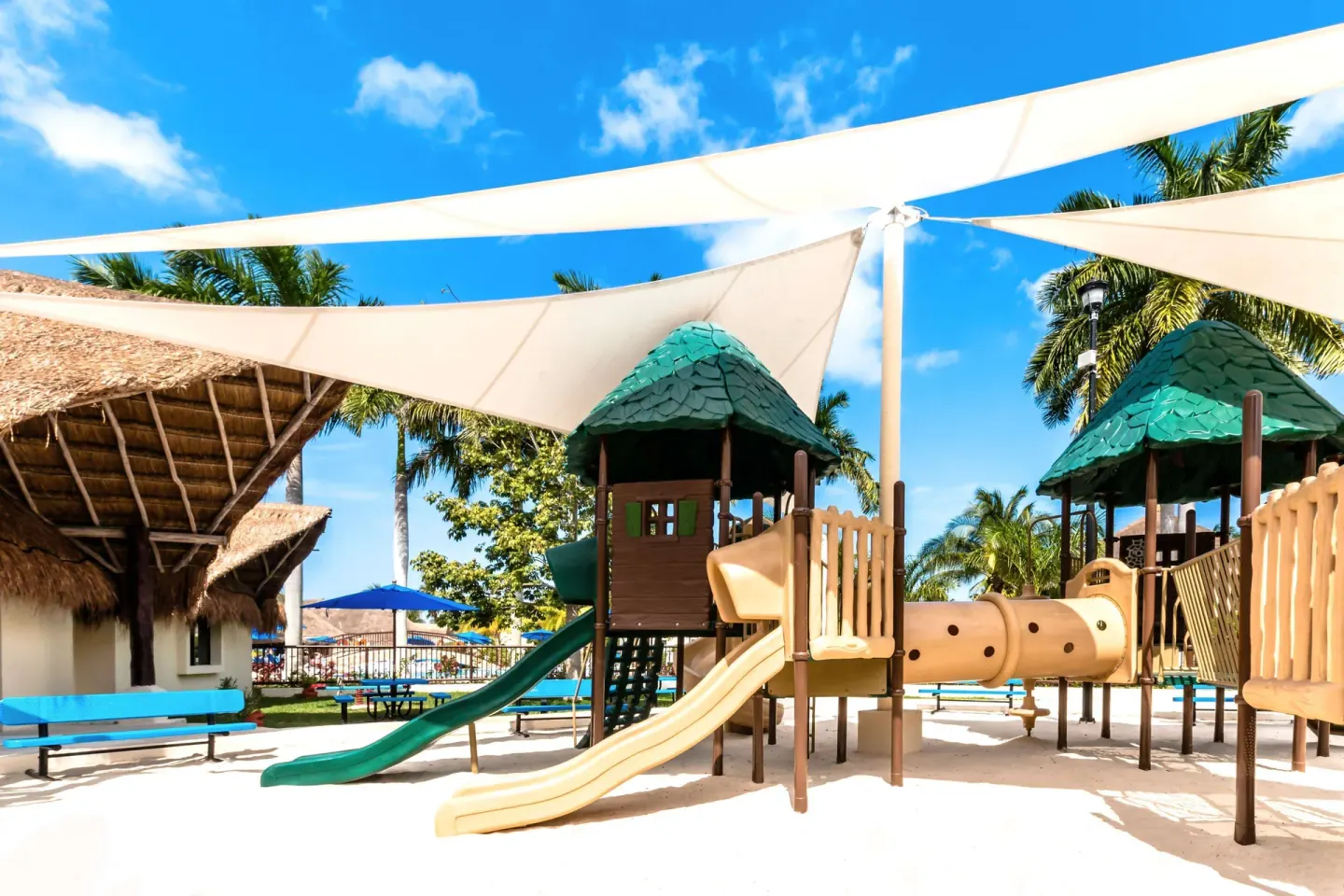 A shaded children's playground with slides and palms is shown at Allegro Cozumel.