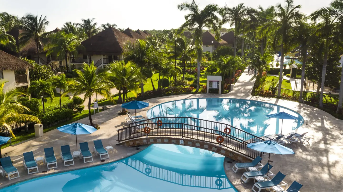 Aerial view of connected pools, loungers, umbrellas, and gardens at Allegro Cozumel.