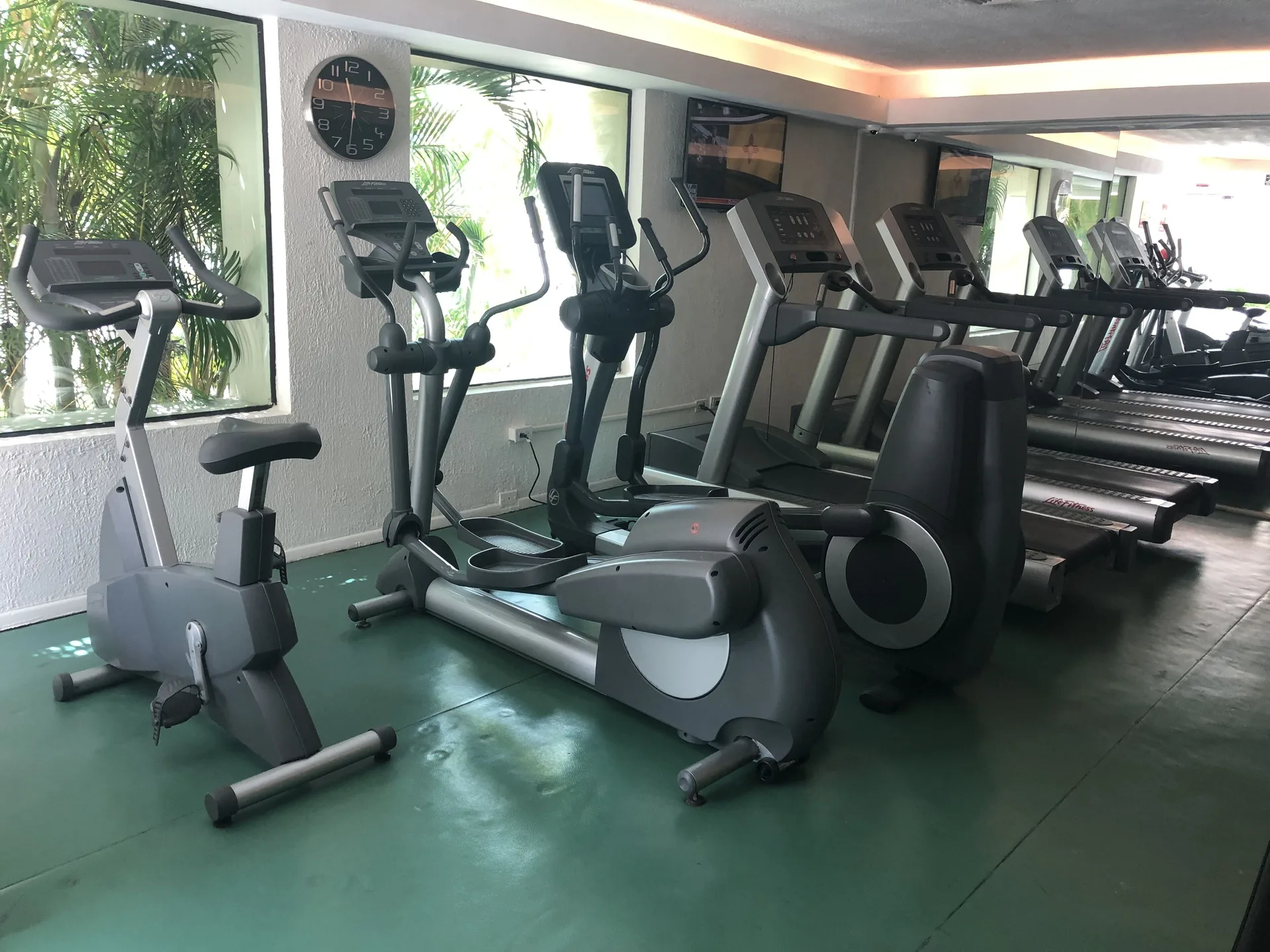 Fitness room with treadmills, bikes, and elliptical machines at Allegro Cozumel.