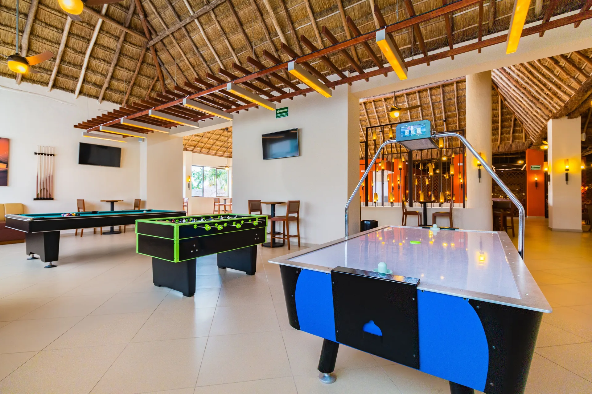 A game room with air hockey, foosball, and pool tables is shown at Allegro Cozumel.