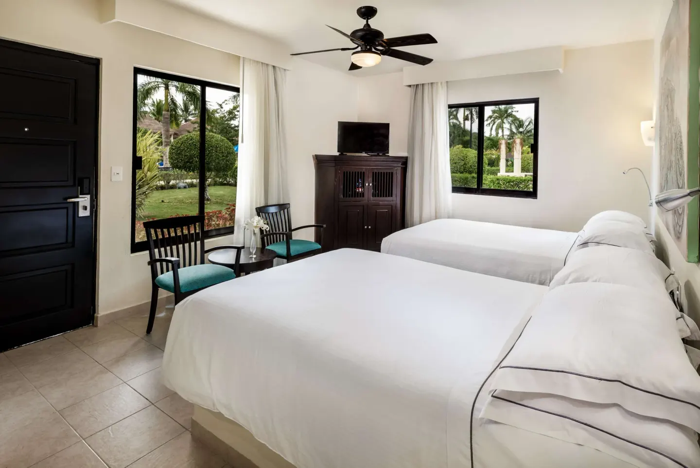 Guest room with two double beds, garden-facing windows and a TV cabinet at Allegro Cozumel.