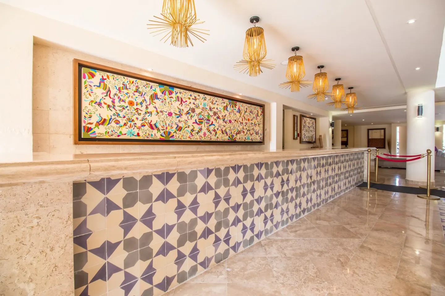 Lobby corridor with patterned tile wall, colorful artwork and pendant lights at Allegro Cozumel.