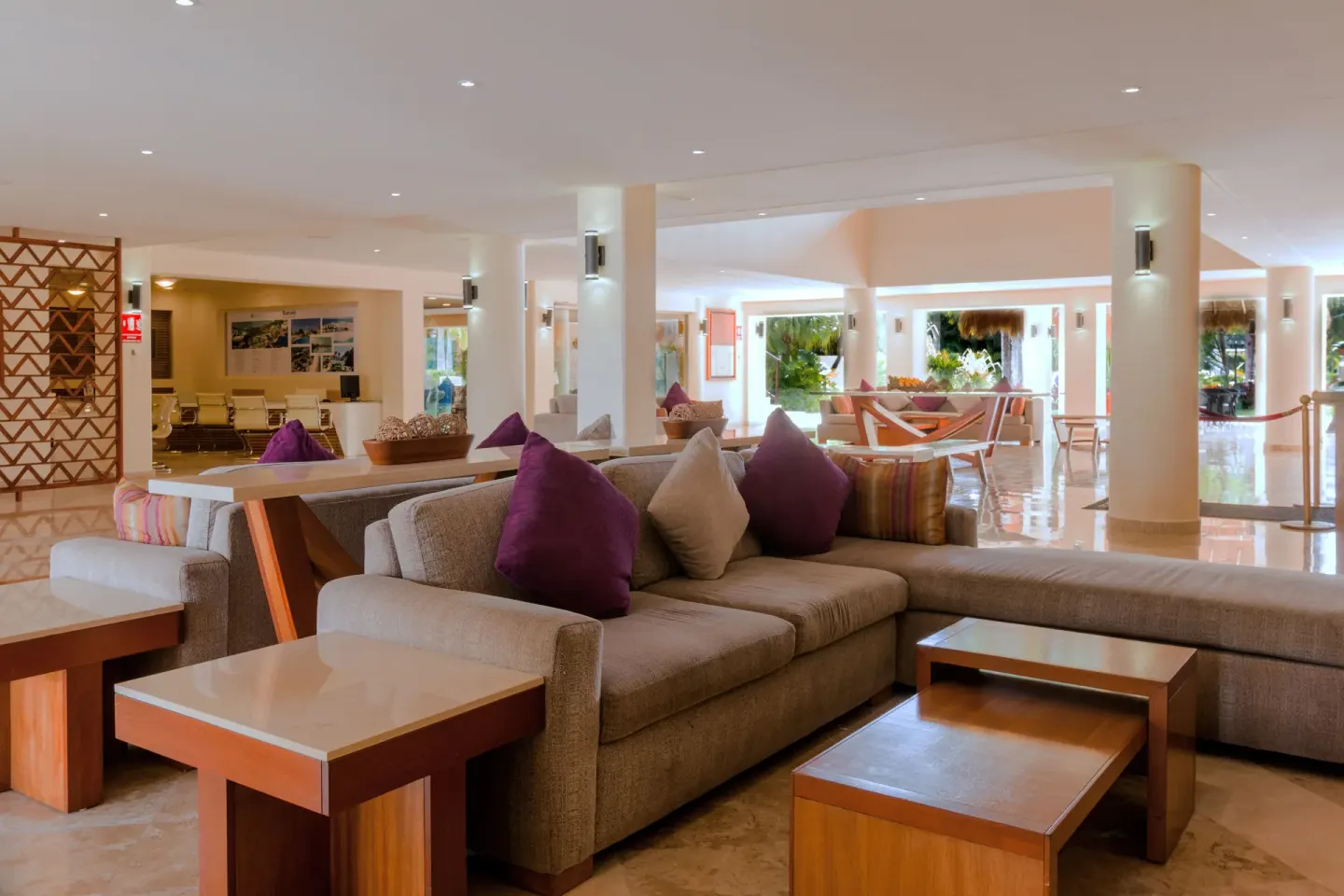 Lobby lounge with sectional sofas, wood tables and purple pillows at Allegro Cozumel.