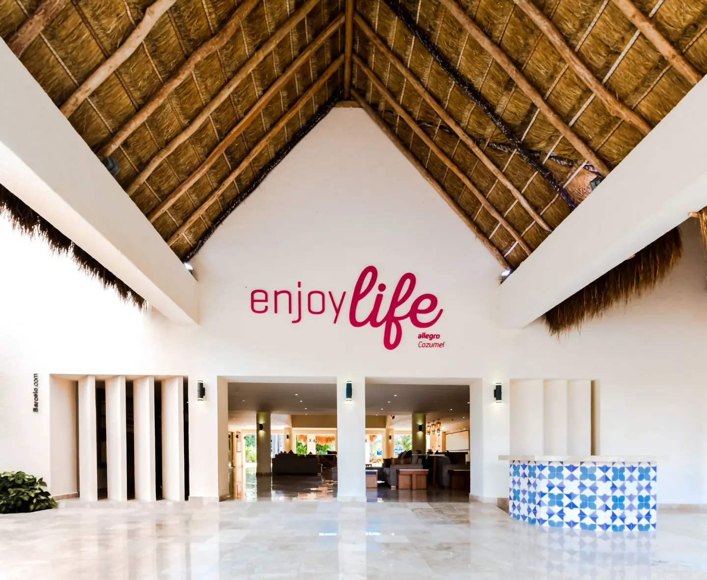 Open-air lobby with thatched ceiling and welcome sign at Allegro Cozumel.