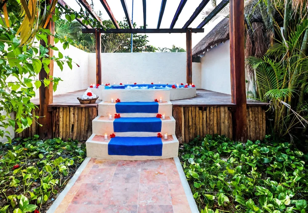 Outdoor spa tub with blue step runners, candles, and flowers at Allegro Cozumel.