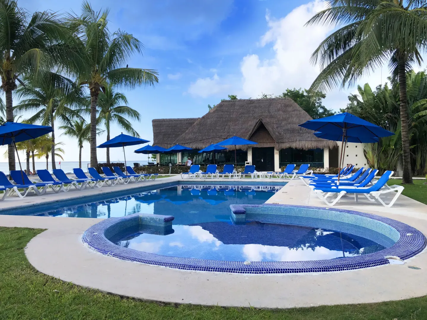 Pool and tiled whirlpool with blue loungers and palms at Allegro Cozumel.