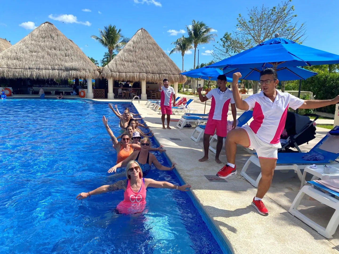 Poolside activity with guests and staff beside blue loungers at Allegro Cozumel.