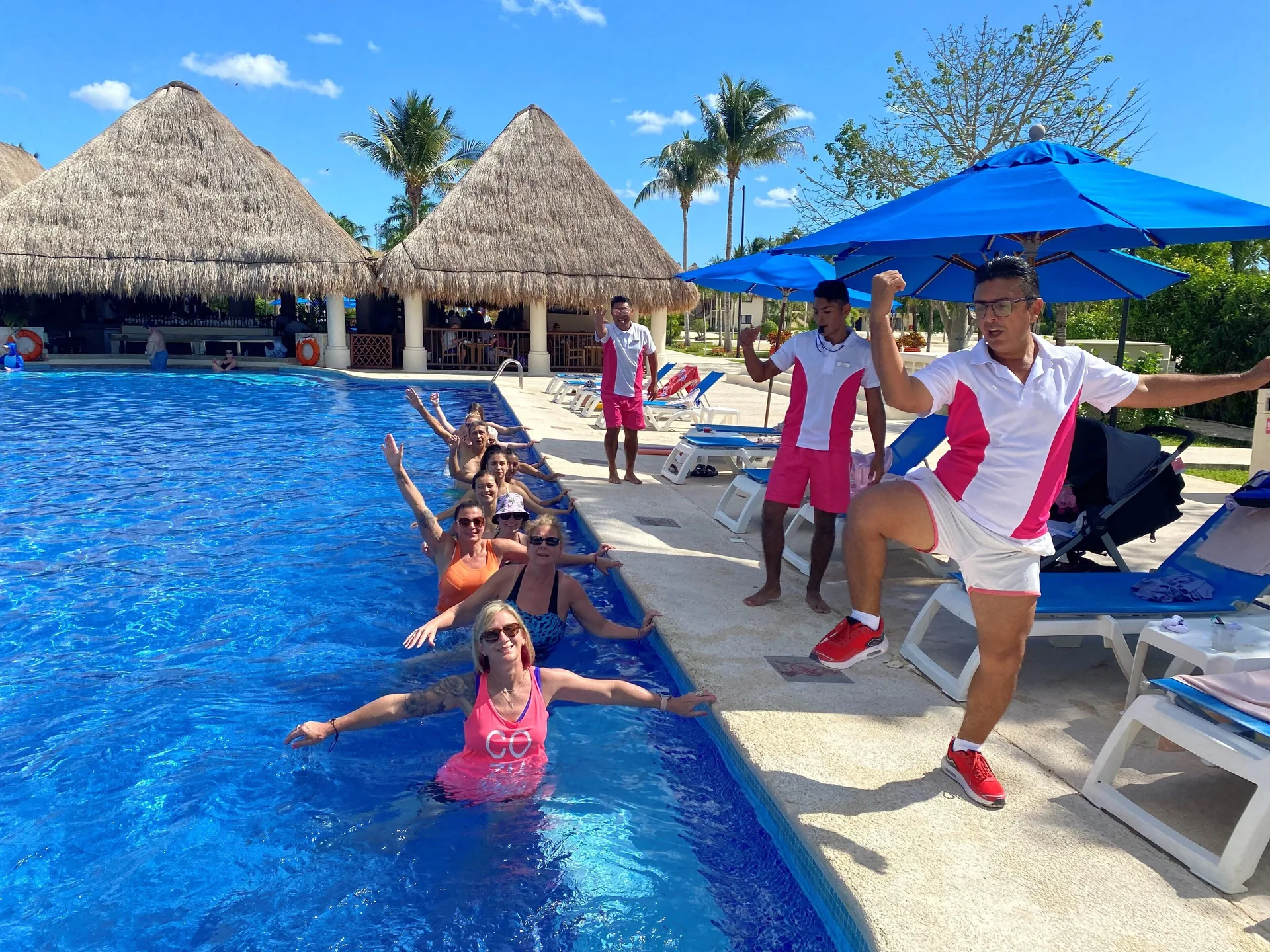 Poolside activity with guests and staff beside blue loungers at Allegro Cozumel.