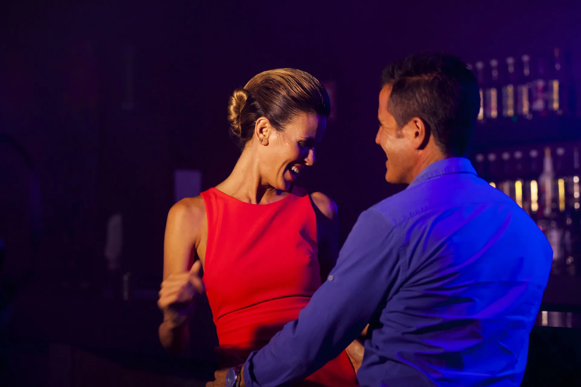 Couple dancing in a dim bar with colorful lighting at Allegro Cozumel.