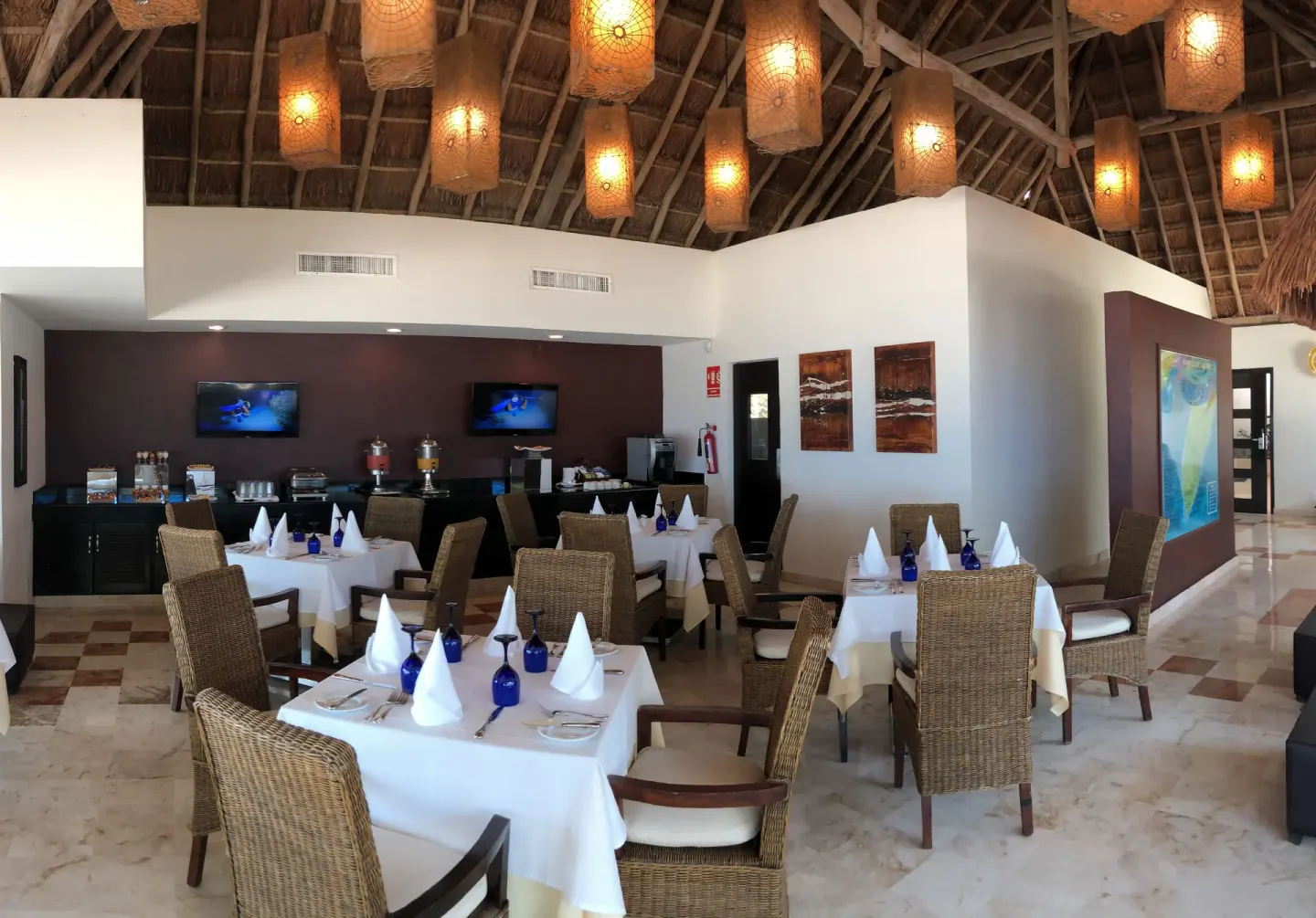 Dining room with buffet counter, white tablecloths, and woven chairs at Allegro Cozumel.