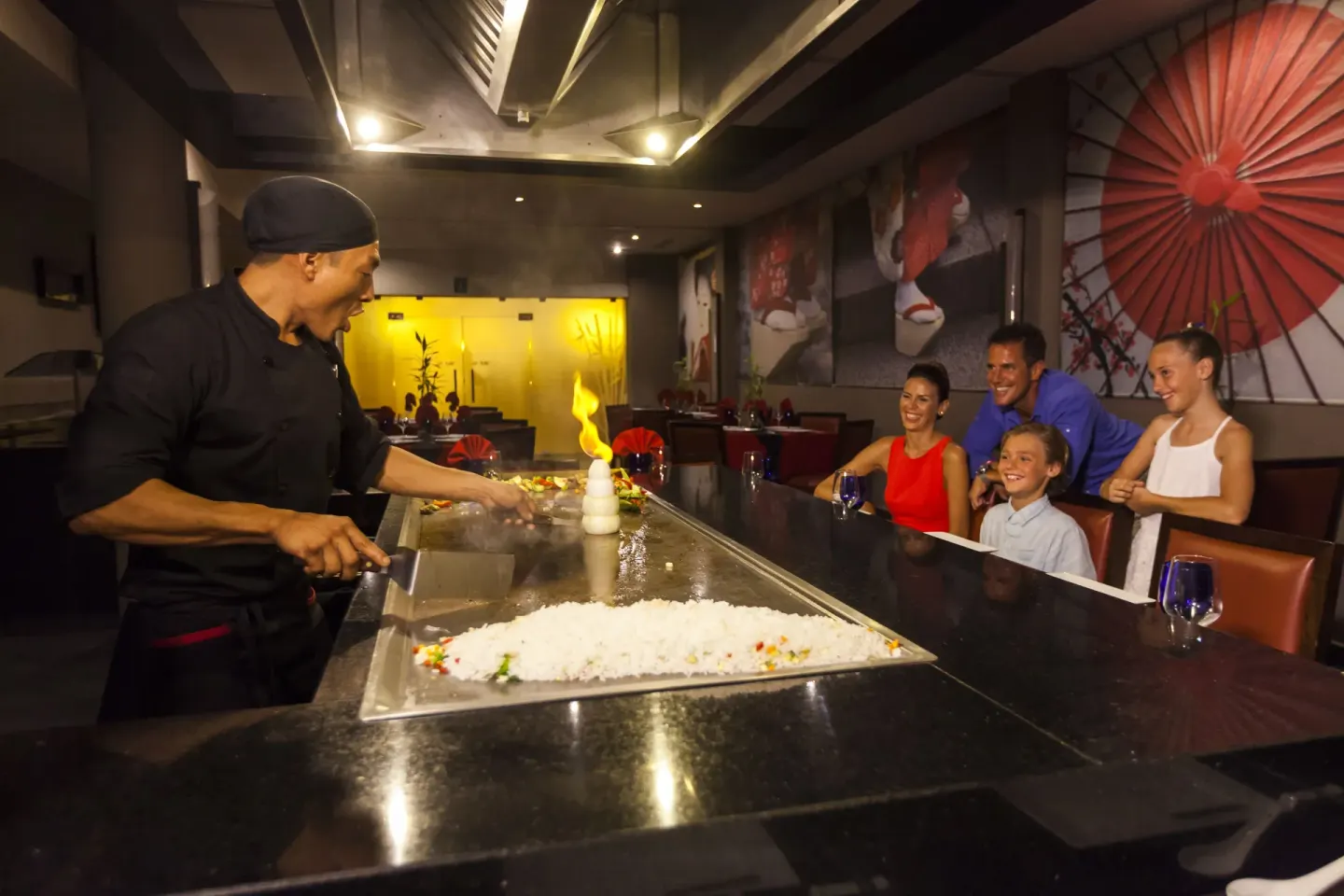 Chef cooks at a teppanyaki grill for a family in Fuji at Allegro Cozumel.