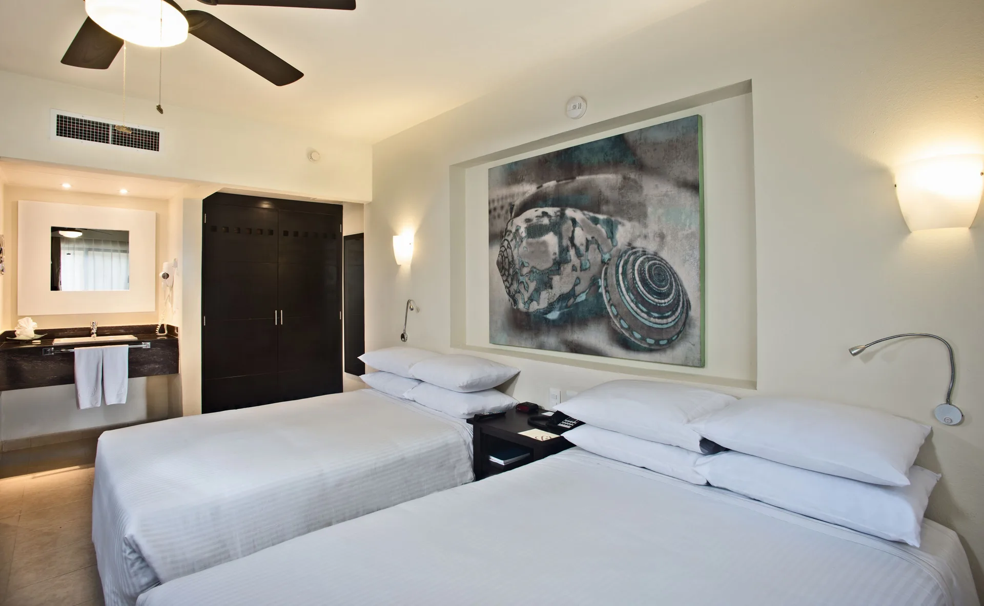 Family Room Garden View with two beds, vanity area, and shell artwork at Allegro Cozumel.
