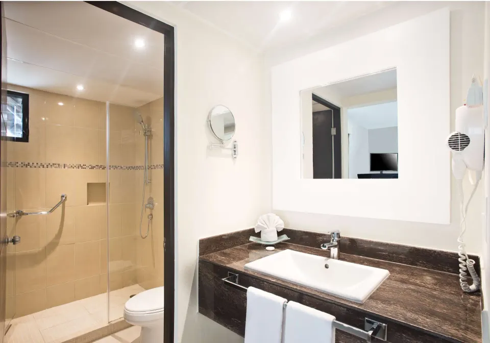 Superior Room bathroom with vanity, mirror, and glass shower at Allegro Cozumel.
