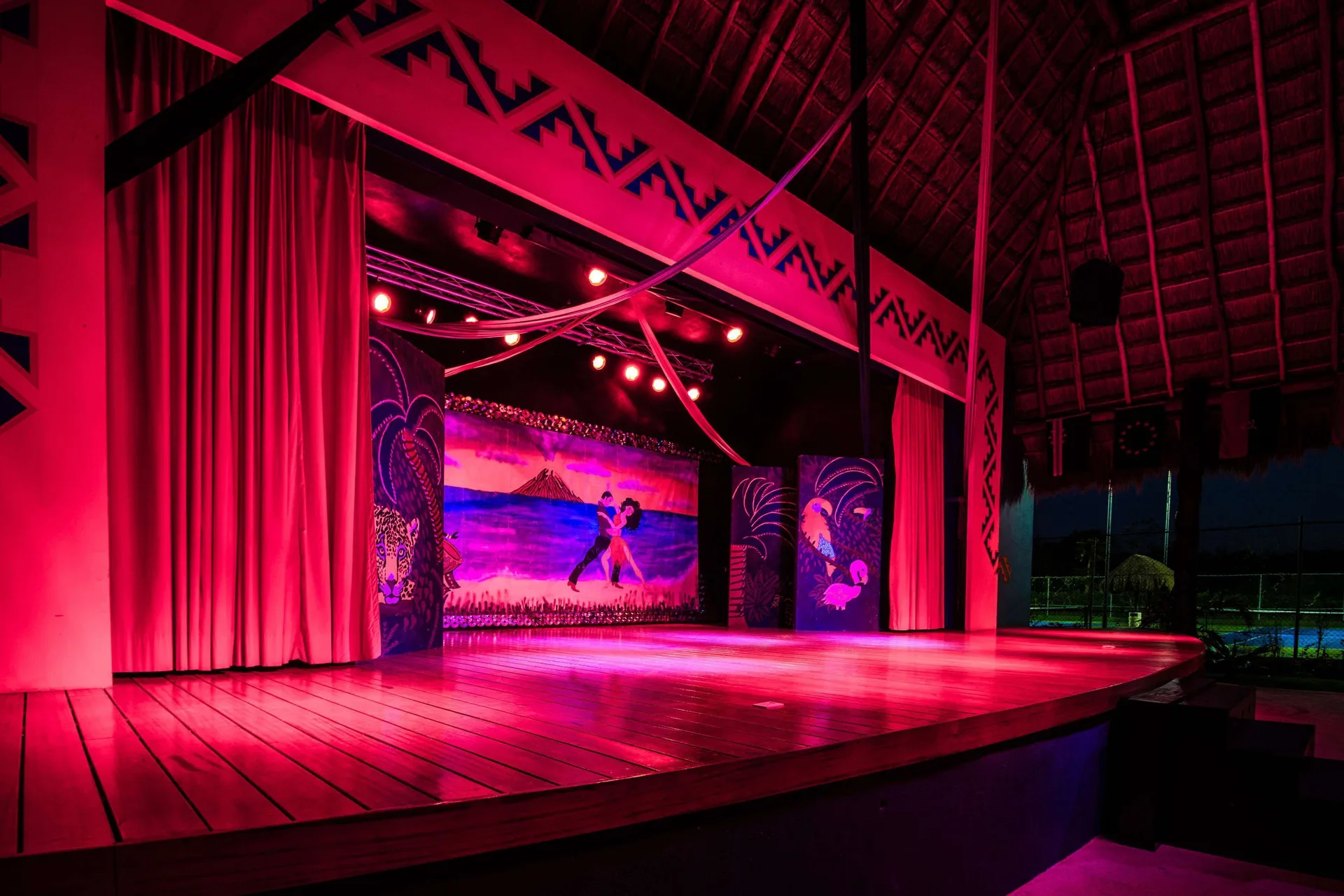 A stage performance is lit in pink and red at Allegro Cozumel.