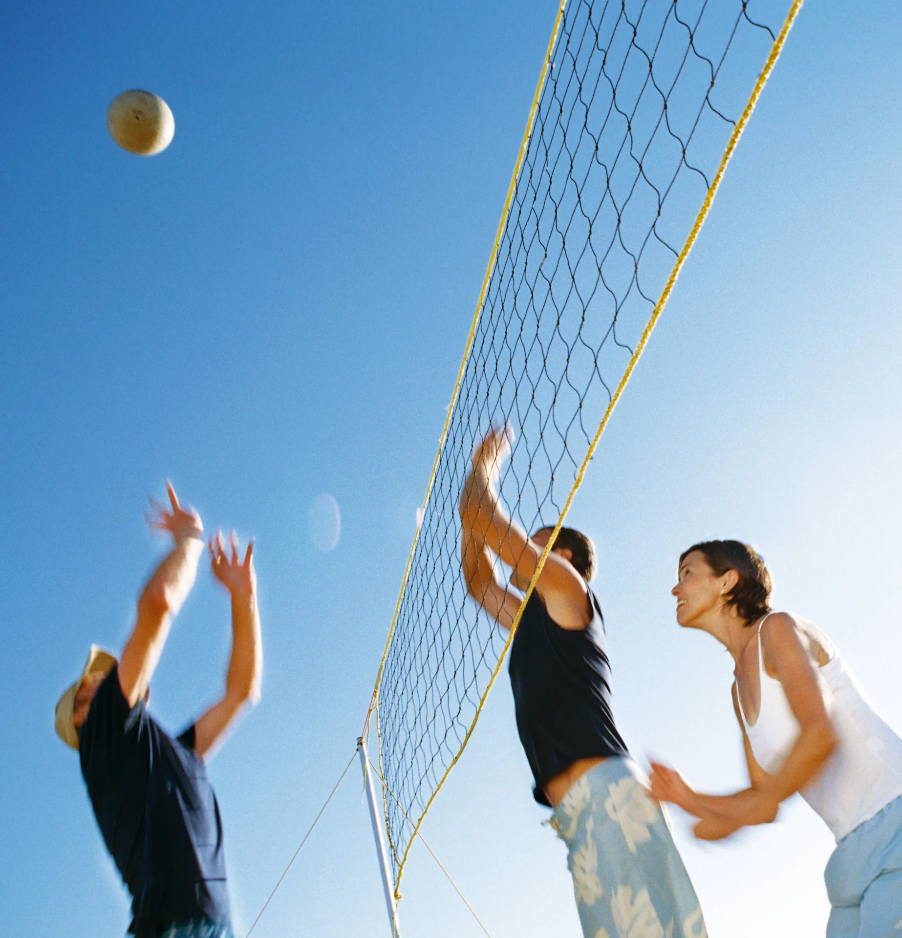 Guests play beach volleyball beside a net under a clear sky at Allegro Playacar.