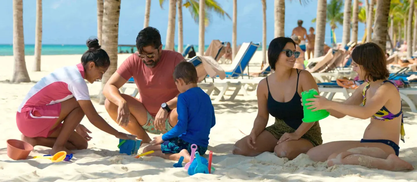 Families play with sand toys beneath palm trees at Allegro Playacar.