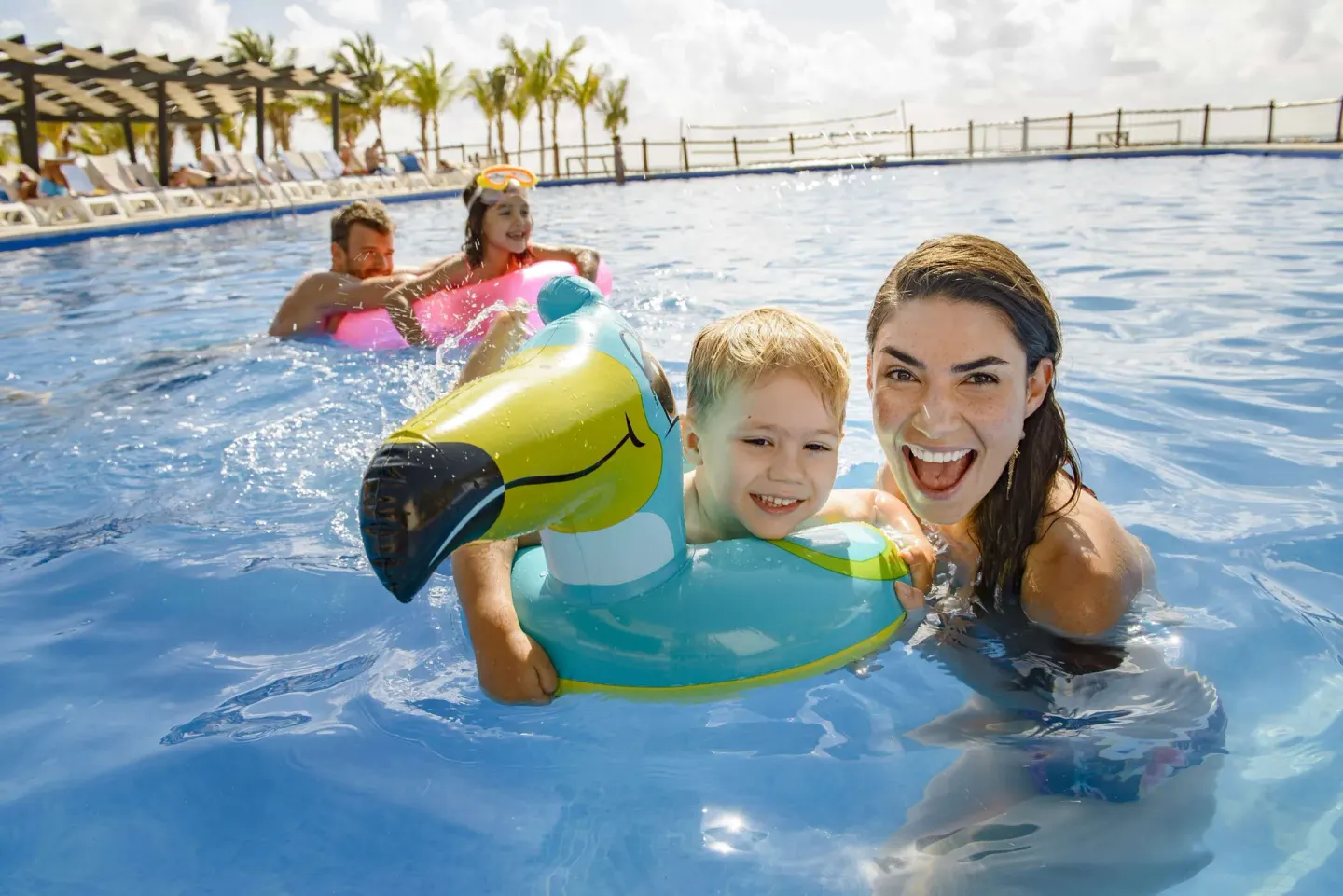 A family smiles in the pool with a colorful float at Allegro Playacar.