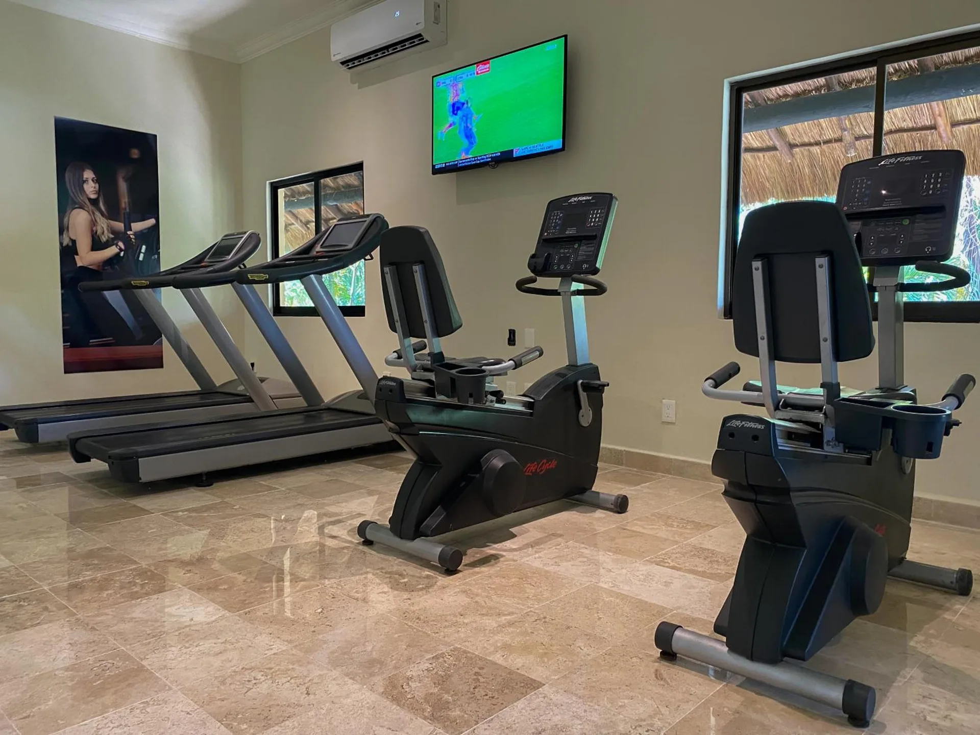 Fitness room with treadmills, exercise bikes, and a wall-mounted TV at Allegro Playacar.