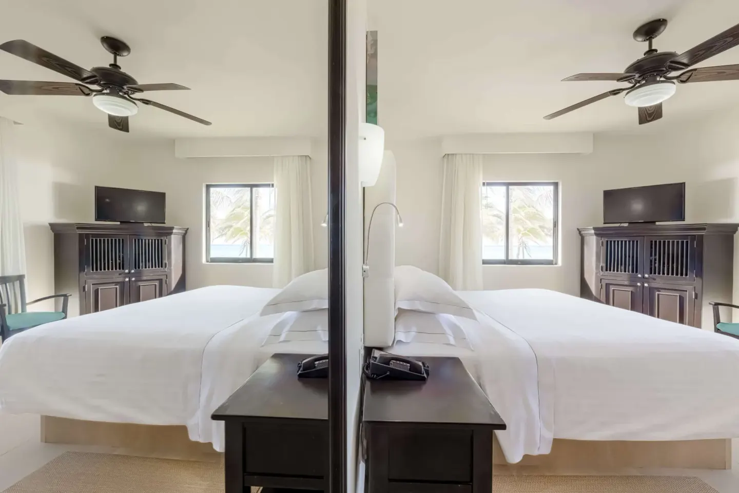 Guest room with a king bed, mirror, TV cabinet, and ceiling fans at Allegro Playacar.