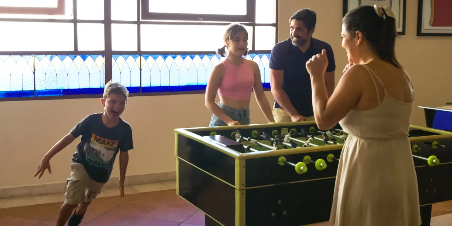 Family plays foosball in an indoor game area at Allegro Playacar.