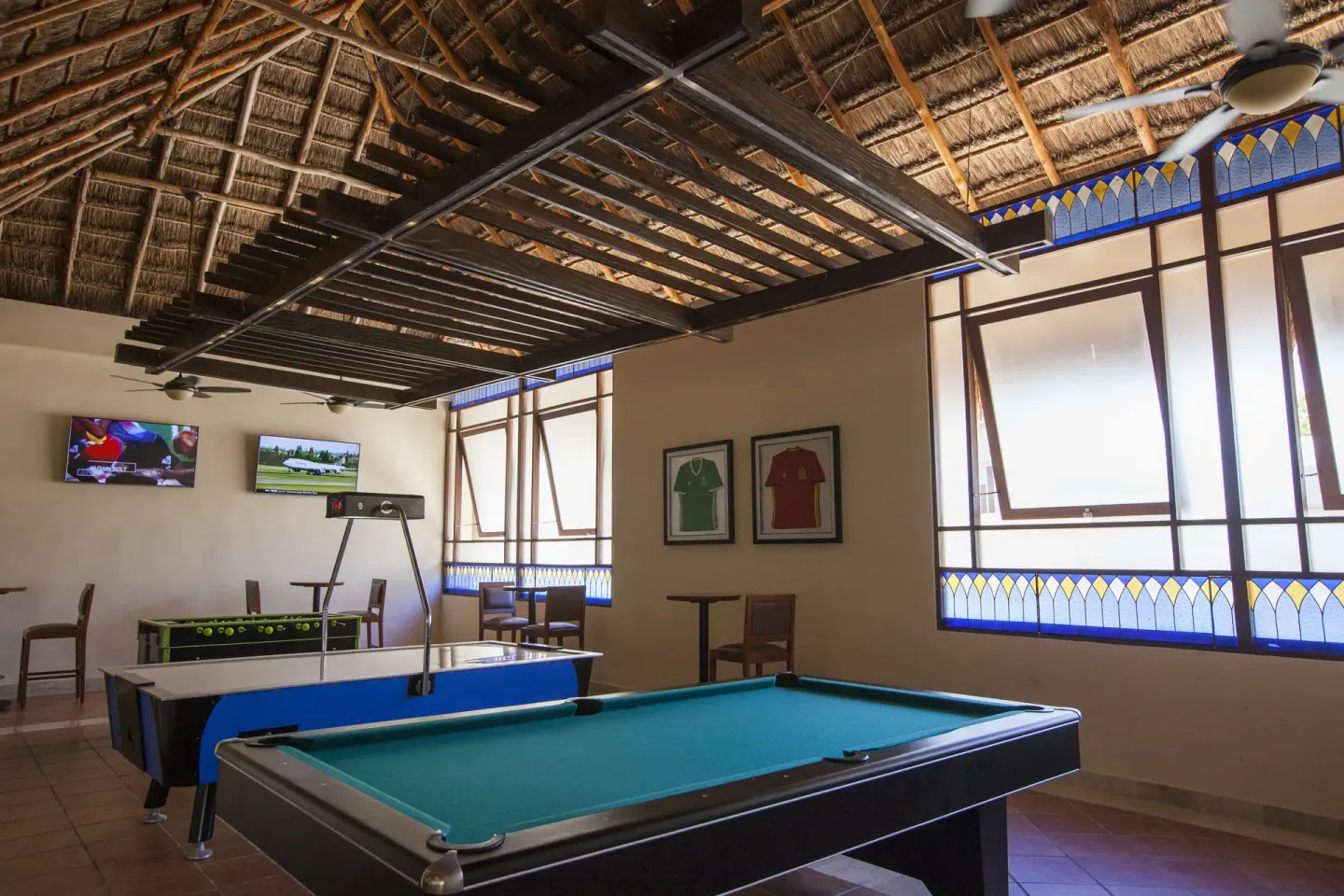 A game room with pool, foosball, air hockey, and televisions at Allegro Playacar.