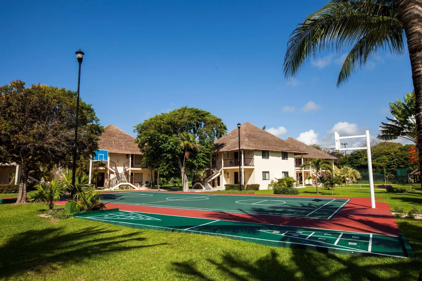 An outdoor basketball court sits among lawns and guest buildings at Allegro Playacar.