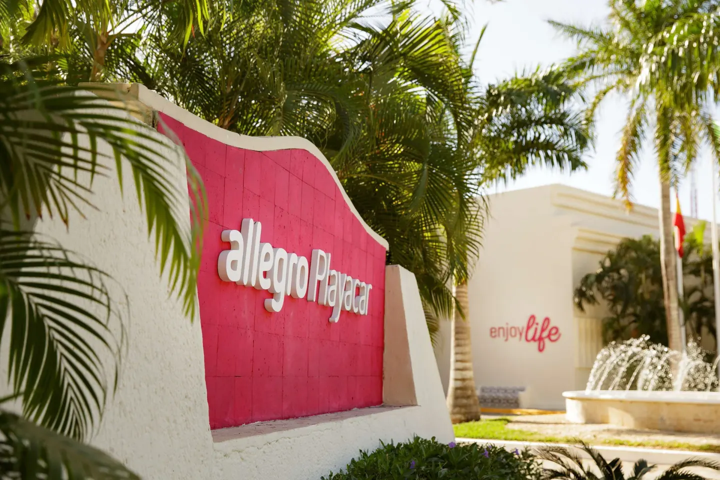 Entrance sign with palms and a fountain at Allegro Playacar.