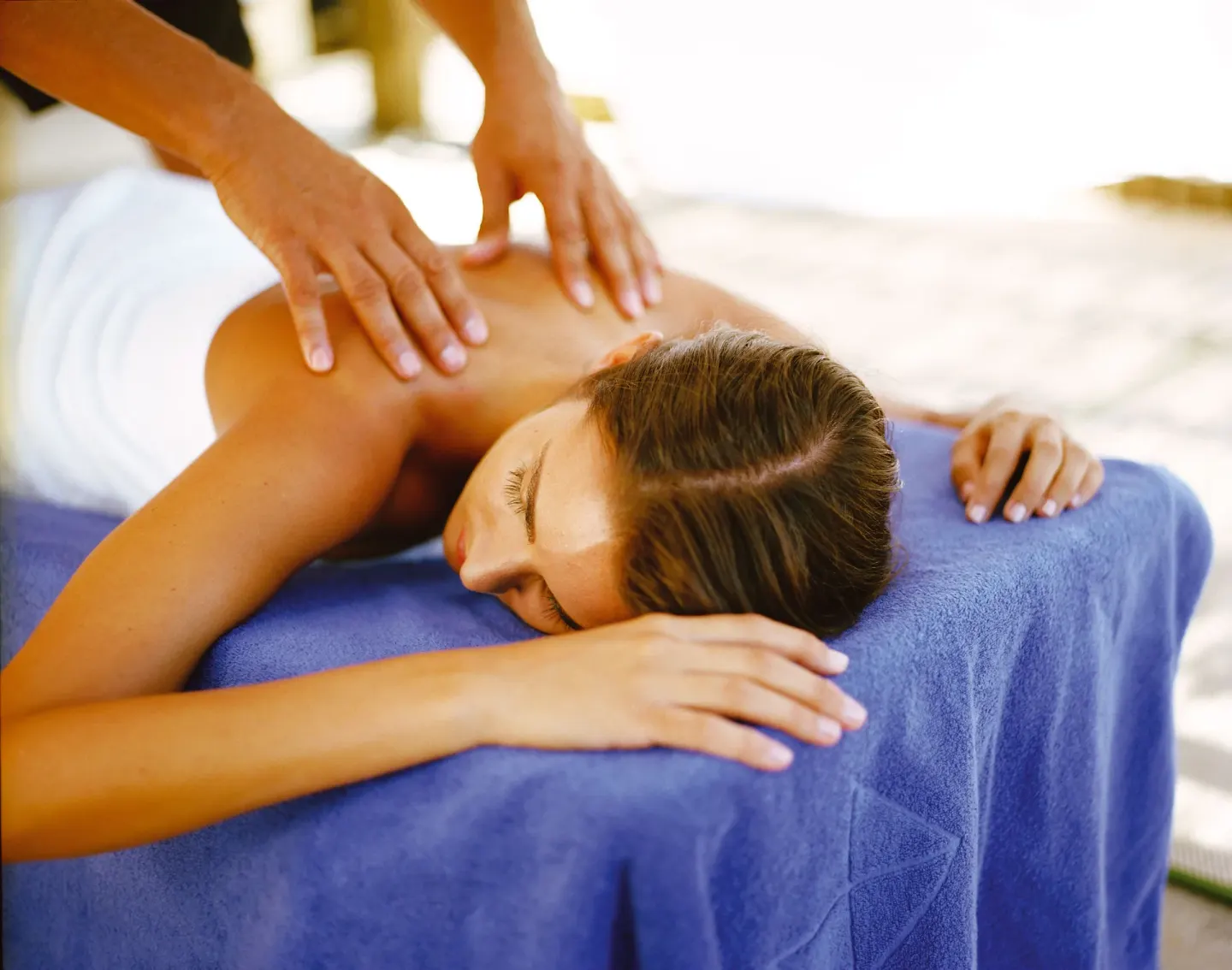 A guest receives a shoulder massage on a blue treatment table at Allegro Playacar.