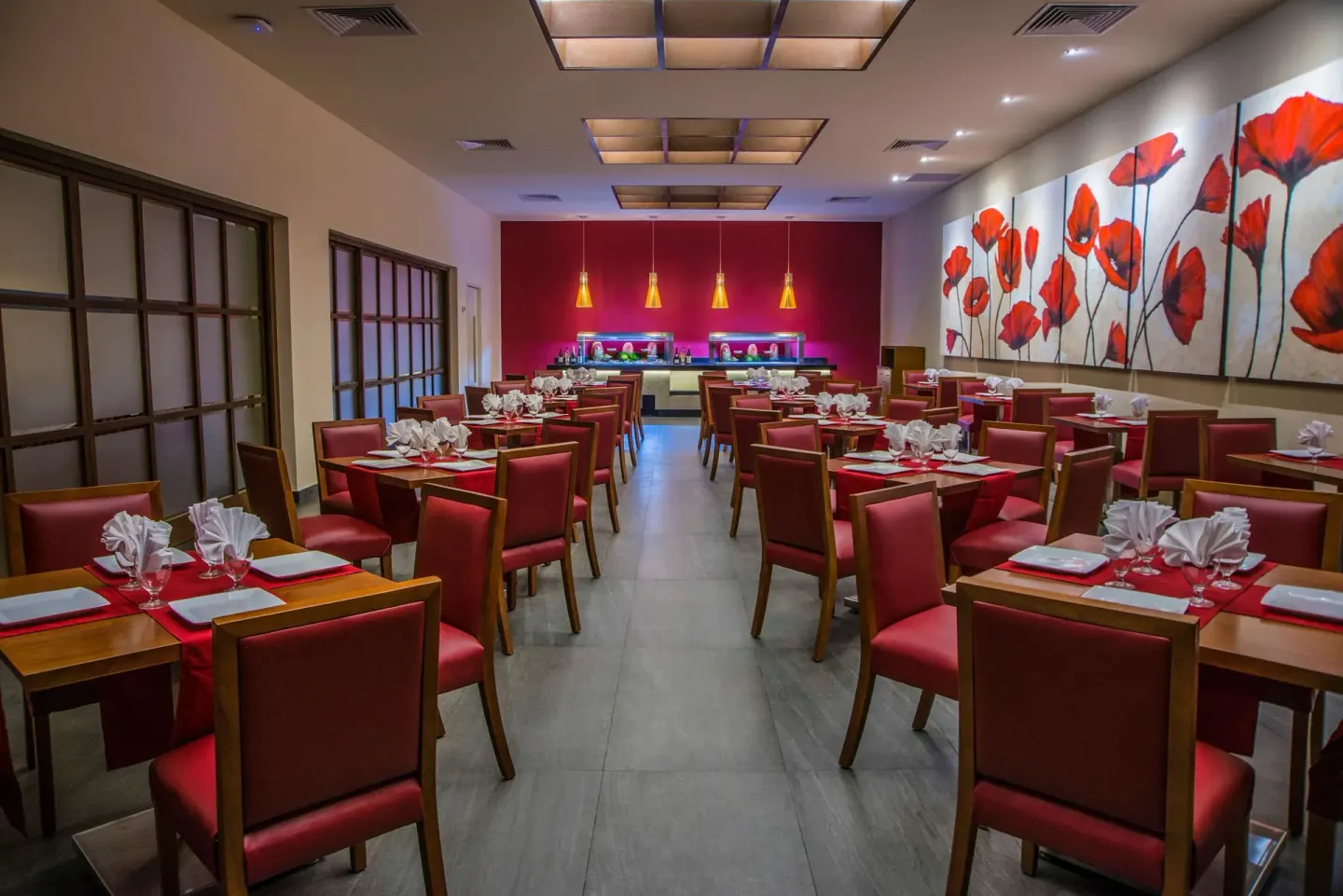 Red-accented restaurant dining room with set tables at Allegro Playacar.