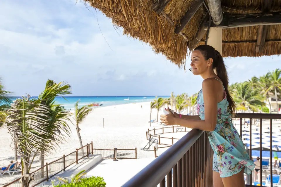 Premium Room balcony with a guest overlooking the beach and ocean at Allegro Playacar.