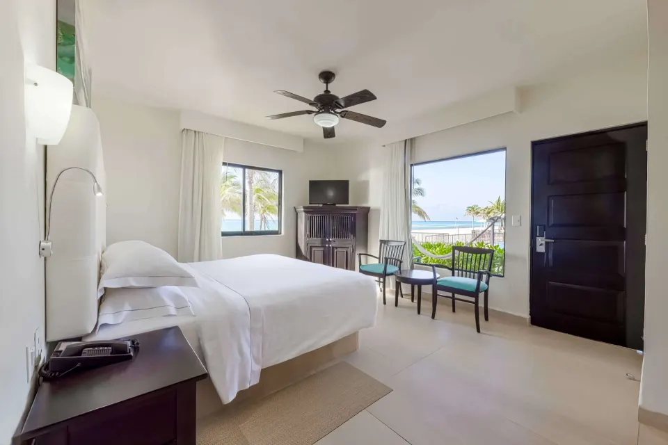 Premium Room with king bed, chairs, TV cabinet, and beach view windows at Allegro Playacar.